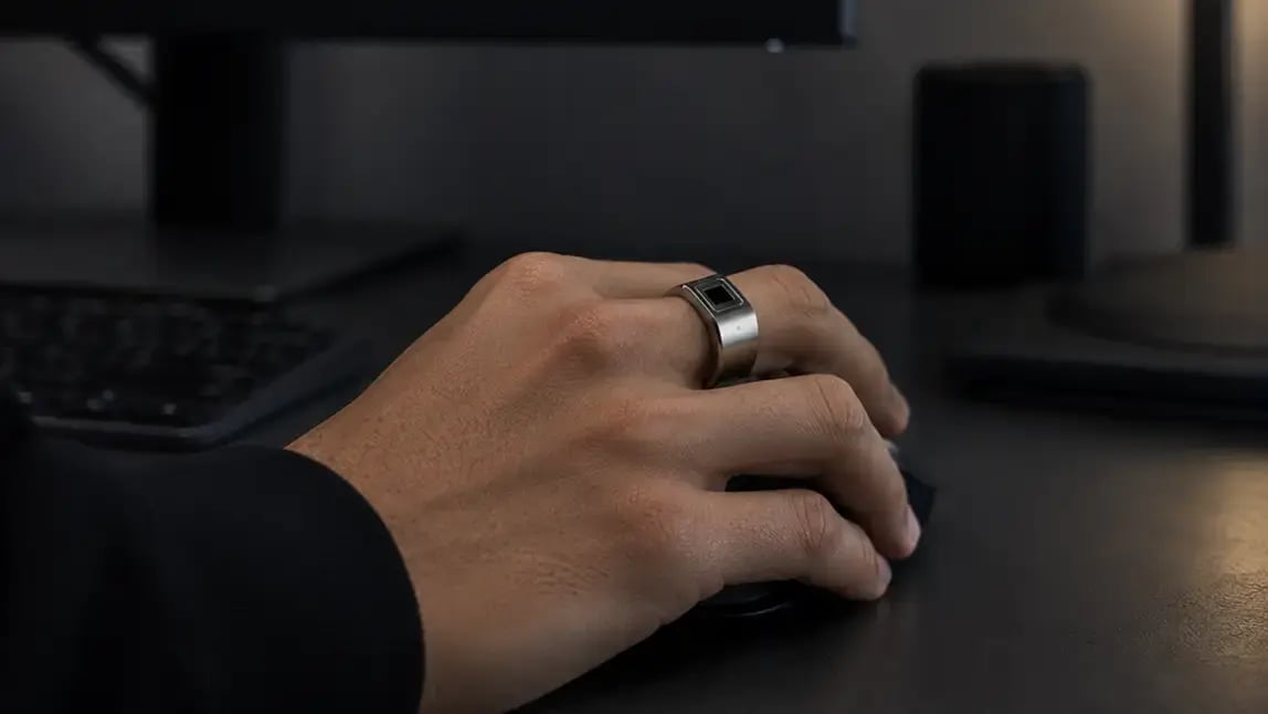 Token Ring worn on a hand resting on a mouse at a desk workstation