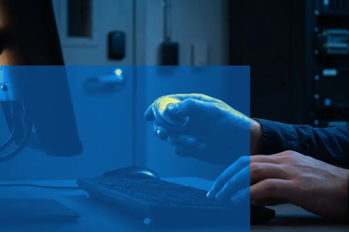 Gloved hands typing on a keyboard in a low-lit room