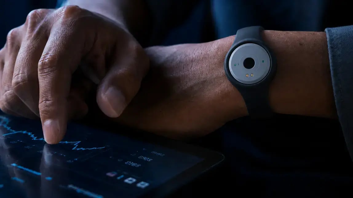 Token wristband on a user's wrist as they interact with a data dashboard on a tablet